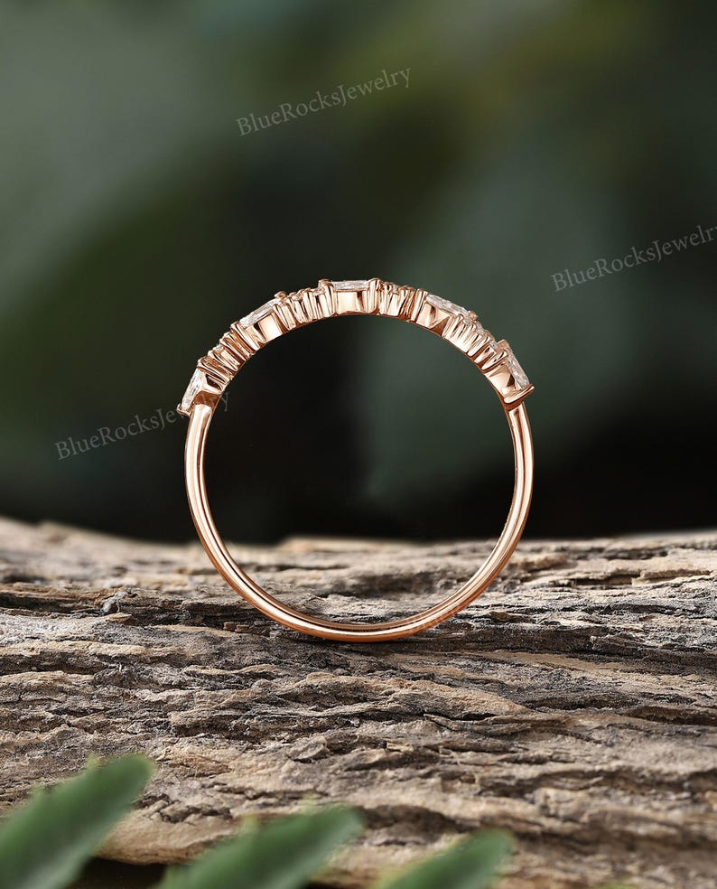 May include: A delicate rose gold band with a row of small, clear, baguette-shaped stones set in a prong setting.