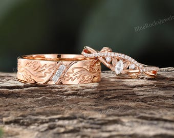 May include: A rose gold wedding band featuring an engraved leaf pattern and three small square-cut diamonds, paired with a matching rose gold ring with a marquise-cut center diamond, smaller round accent stones, and a twisted vine-like band.