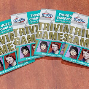 Puede incluir: Cinco copias de un juego de trivia basado en el programa de televisi&oacute;n "Three's Company". El juego se llama "Trivia Showdown!" y presenta a los personajes del programa en la portada. El sitio web www.triviapartygames.com est&aacute; impreso en la parte inferior de cada portada.
