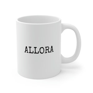 May include: White ceramic mug with a black inscription that reads "ALLORA".
