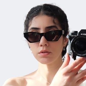 Versace 477/A vintage sunglasses worn on face, featuring black frame, silver Medusa logos and futuristic 90s designer style.
