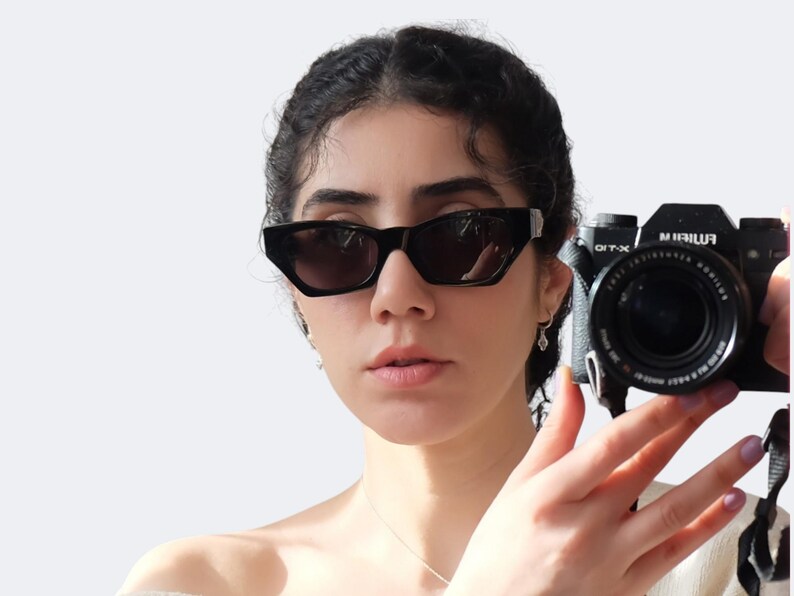 Versace 477/A vintage sunglasses worn on face, featuring black frame, silver Medusa logos and futuristic 90s designer style.