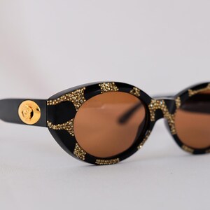 Ultra-rare 1990s vintage Versace MOD. 480 vintage sunglasses in deadstock mint condition – featuring luxurious coral-effect frames, Swarovski crystal embellishments, and iconic gold Medusa logos on both temples, complete with original Versace case, cloth, and authentication card.