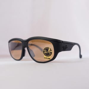 May include: Black Ray-Ban sunglasses with brown lenses and a gold sticker that says "Ray-Ban G-15 Lens".
