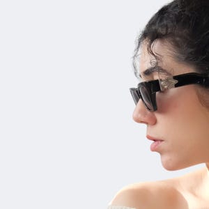Versace 477/A vintage sunglasses worn on face, featuring black frame, silver Medusa logos and futuristic 90s designer style.