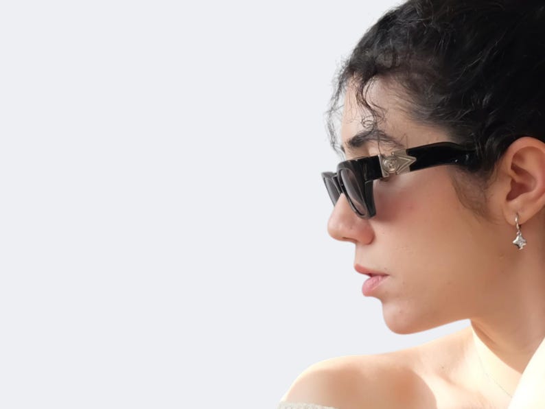 Versace 477/A vintage sunglasses worn on face, featuring black frame, silver Medusa logos and futuristic 90s designer style.