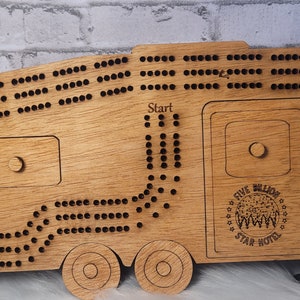 May include: Wooden game board shaped like a camper van with a game track and holes for marbles. The board has a "Start" and "Finish" label and a logo that says "Five Billion Star Hotel".