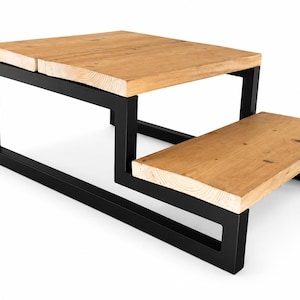 May include: A two-tiered coffee table with a natural wood top and a black metal frame. The top is made of two rectangular wooden planks. The lower tier is a smaller, rectangular platform. The table is approximately 48 inches long.