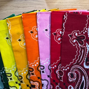 Puede incluir: Una colecci&oacute;n de pa&ntilde;uelos coloridos en tonos verdes, amarillos, naranjas, rosas y rojos. Cada pa&ntilde;uelo presenta un dise&ntilde;o de cachemira blanco. Los pa&ntilde;uelos est&aacute;n doblados y apilados, mostrando sus colores y patrones vibrantes.