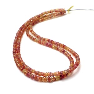 May include: A strand of red and yellow gemstone beads. The beads are faceted and have a slightly irregular shape. The strand is strung on a thin wire.