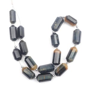 May include: Strand of faceted, dark blue and brown gemstone beads. The beads are strung on a thin, silver-colored wire and separated by small, silver-colored beads. The gemstones have a polished, rectangular shape.