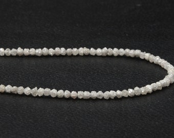May include: A strand of white rough diamonds strung together on a black background.