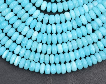 May include: A close-up of a strand of light blue turquoise beads. The beads are oval shaped and have a smooth, polished finish.