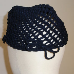 May include: A navy blue crocheted hat with a bow on the back.