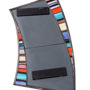 May include: A curved, gray mirror with a stained glass border. The border features colorful stripes in shades of blue, red, orange, yellow, and white. The mirror has two black metal hanging brackets on the back.