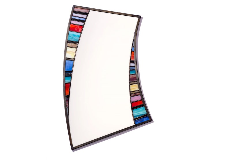 May include: A curved mirror with a colorful mosaic frame. The frame is made of small, rectangular pieces of glass in various shades of blue, red, yellow, and green.