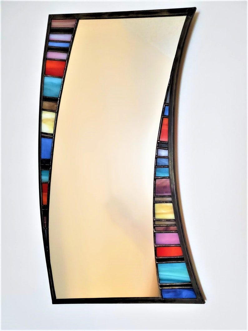 May include: A curved mirror with a black frame and a colorful stained glass border. The border features a variety of colors, including red, blue, green, yellow, and purple.