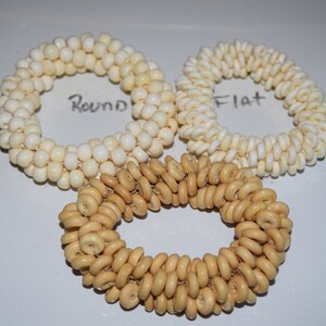 May include: Three wooden bead bracelets, one with round beads labeled "Round", one with flat beads labeled "Flat", and one with donut-shaped beads.