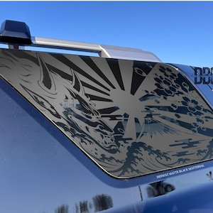 May include: Matte black car window decal featuring a Japanese-inspired design. The artwork includes a dragon, sun rays, waves, and cherry blossoms. The text "DEFAULT MATTE BLACK MATERIAL" is visible.