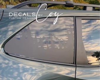 May include: A dark green vehicle features a black vinyl decal on the rear side window. The decal displays a silhouette of a mountain range and pine trees. The text DECALS BY COY CUSTOM DESIGNS is printed in white above the mountain graphic.