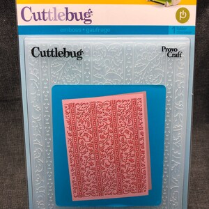 May include: A white plastic embossing folder with a floral design. The folder is labeled "Cuttlebug" and "Provo Craft".