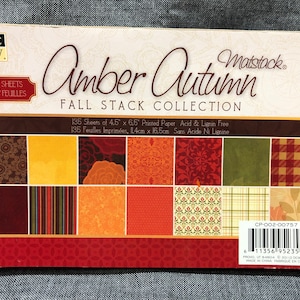 May include: A package of 135 sheets of 4.5 x 6.5 inch printed paper in a fall theme. The paper is acid and lignin free. The package shows a variety of patterns in shades of red, orange, yellow, brown, and green. The text on the package reads "Amber Autumn Fall Stack Collection" and "Matstack".