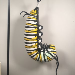 Hanging J Monarch Caterpillar Sculpture, 14 inches tall, made of paper mache clay and polymer clay. Painted with acrylic.