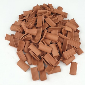 May include: A pile of terracotta clay pieces, broken into various shapes and sizes. The pieces are a reddish-brown color and have a rough, textured surface.