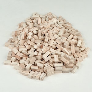 May include: A large pile of small, unfinished wooden blocks. The blocks are all roughly the same size and shape, and they are arranged in a random pattern. The blocks are a light brown color.