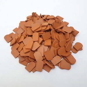 May include: A large pile of terracotta roof tiles. The tiles are a reddish-brown color and have a slightly curved shape.