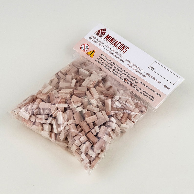 Może przedstawiać: Torebka z małymi, beżowymi i brązowymi płytkami ceramicznymi. Torebka jest oznaczona "Miniacons" i zawiera stronę internetową oraz dane kontaktowe firmy.