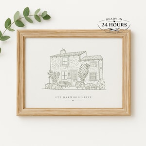 May include: A framed house sketch in a light wood frame. The black and white drawing depicts a detailed illustration of a house with a stone facade, surrounded by plants. The text "123 OAKWOOD DRIVE" is at the bottom.