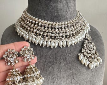 Könnte beinhalten: Ein silbernes und weißes Braut-Halsketten-Set mit Perlenakzenten. Das Set beinhaltet eine Choker-Halskette, Ohrringe und einen Anhänger.