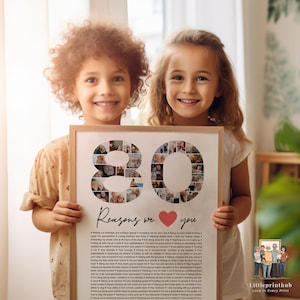 May include: A framed photo collage of 80 reasons to love someone. The collage is made up of small photos arranged in the shape of the number 80. The frame is white and has a black mat. The photo is surrounded by two children holding the frame. The text below the collage reads "80 Reasons we love you".