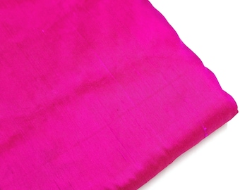 Puede incluir: Una tela de seda rosa fucsia vibrante, lisa y brillante, doblada cuidadosamente.