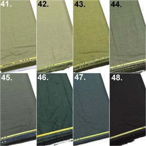 May include: A collection of eight fabric swatches labeled 41 through 48, displaying various shades of green, gray, and black. Each piece of fabric features a visible woven texture and a yellow selvage edge with the text 100% PREMIUM.