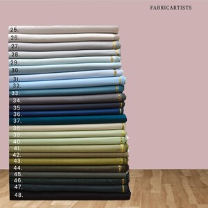 May include: A vertical stack of folded fabric bolts labeled with numbers 25 through 48, displaying a gradient of colors ranging from light gray and blue to various shades of green, olive, brown, and dark charcoal, with the text FABRICARTISTS.