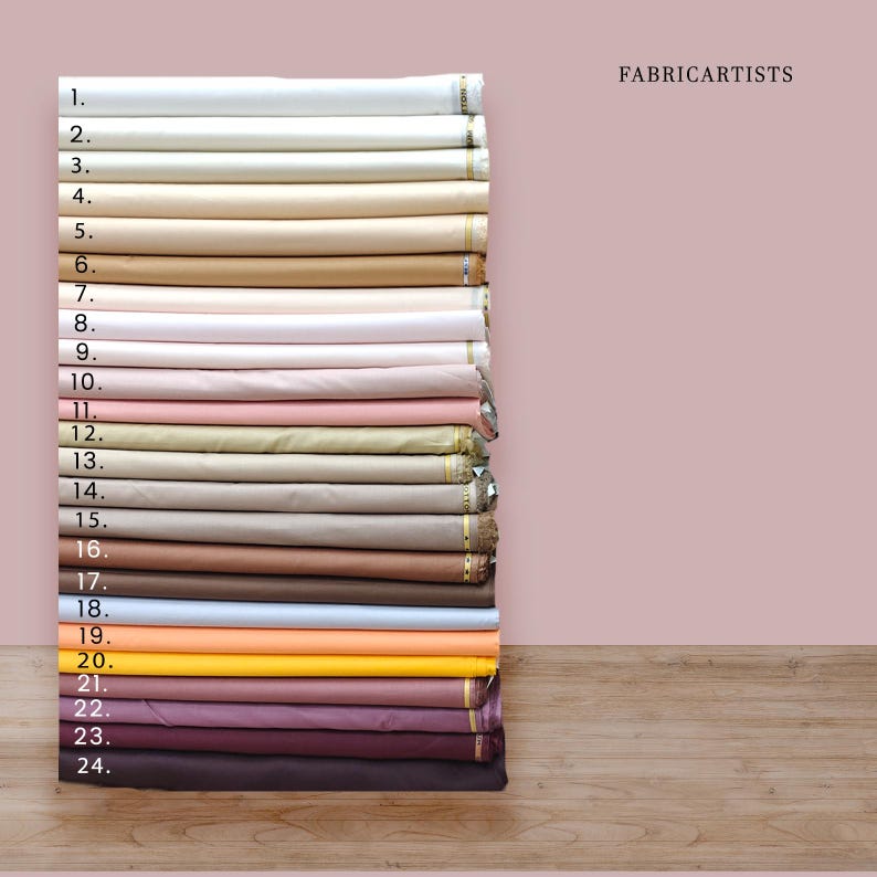 May include: A stack of twenty-four folded fabric bolts arranged vertically, labeled with numbers one through twenty-four. The collection features a gradient of solid colors ranging from white and cream to beige, pink, blue, yellow, and dark brown.