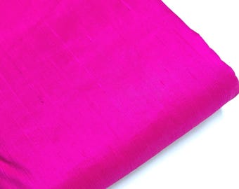May include: A bright pink fabric with a subtle, textured, striped pattern. The fabric is folded in half and the corner is visible.
