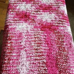 May include: A pink and white crocheted blanket with a striped pattern. The blanket is made with a soft, fluffy yarn.