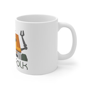 May include: White ceramic mug featuring a cartoon illustration of a robot with an orange body and green legs. The text "Folk" is printed below the robot.