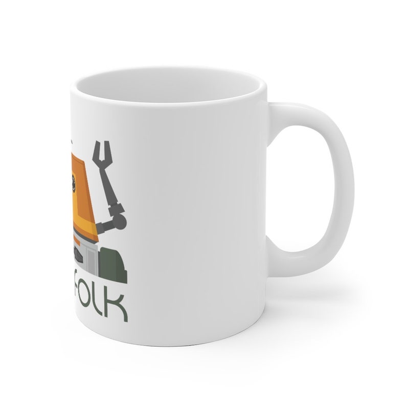 May include: White ceramic mug featuring a cartoon illustration of a robot with an orange body and green legs. The text "Folk" is printed below the robot.