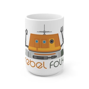 May include: White ceramic mug with a cartoon illustration of a droid with orange, gray, and blue details. The text "Rebel Folk" is printed on the mug.