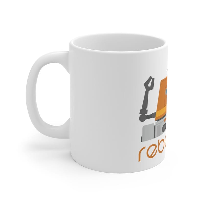 May include: White ceramic mug featuring a cartoon illustration of a robot with an orange body and the word "rebels" in orange text.