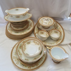 May include: A set of vintage fine china dinnerware with a floral pattern and gold trim. The set includes plates, bowls, a creamer, a sugar bowl, and a gravy boat.