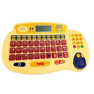 May include: A yellow VTech Phonics Reading Center with a keyboard layout featuring alphabet keys, number keys, and a small screen. The device has a blue trackball and a "help" button.