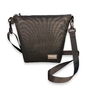 May include: A dark gray mesh crossbody bag with a zippered top closure and an adjustable nylon strap attached by metal swivel clips. A small rectangular label on the front features the text TOPSIDE by DIVE GEEK in white lettering.