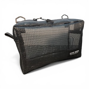 May include: A black rectangular mesh storage bag with a zippered top closure and two metal D-rings at the top. The bag features a small black label in the bottom right corner with the white text DIVE GEEK and the smaller text Bags for Busy Divers.