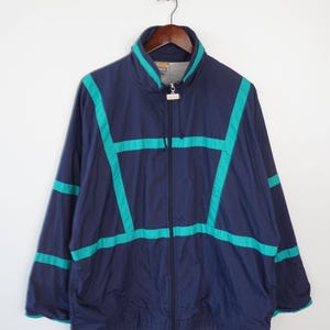 May include: A navy blue jacket with a zipper closure and green accents. The jacket has a stand-up collar and a drawstring at the bottom.