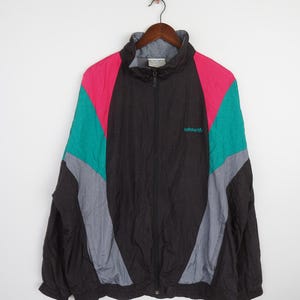 May include: A black, grey, teal and pink colour-blocked windbreaker jacket with a zip closure and the Adidas logo on the front.